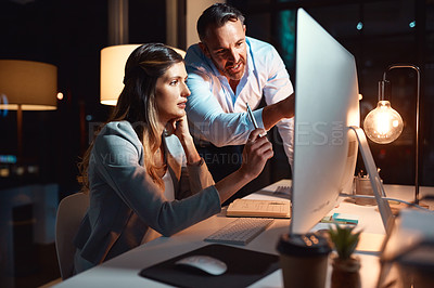 Buy stock photo Shot of a businessman and businesswoman using a computer during a late night at work