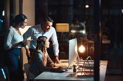 Buy stock photo Shot of a group of businesspeople using a computer during a late night at work