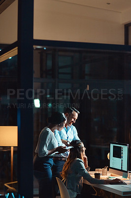 Buy stock photo Shot of a group of businesspeople using a computer during a late night at work