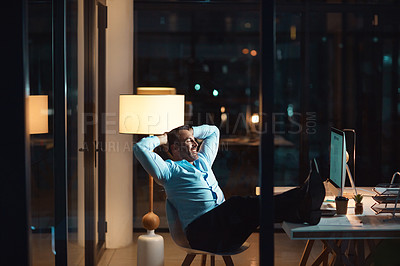 Buy stock photo Shot of a mature businessman relaxing at his desk during a late night at work