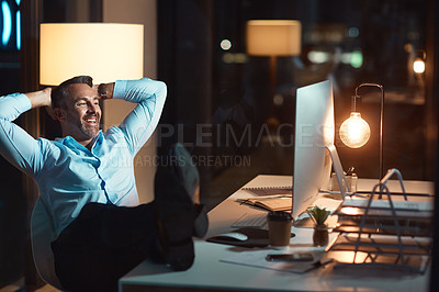 Buy stock photo Shot of a mature businessman relaxing at his desk during a late night at work