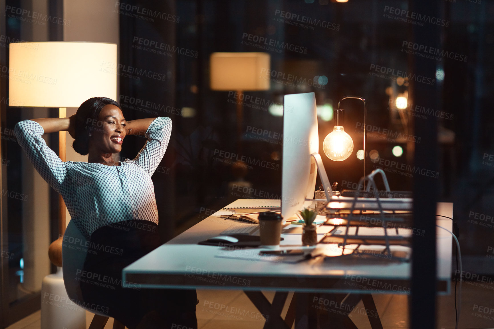 Buy stock photo Shot of a young businesswoman relaxing at her desk during a late night at work