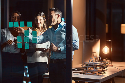 Buy stock photo Shot of a group of businesspeople having a brainstorming session at night in a modern office