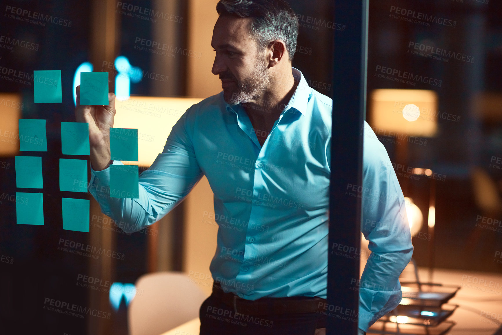 Buy stock photo Night, writing and business man with glass board for strategy, project ideas or brainstorming in corporate office. Dark, sticky note and male employee with marker for planning, agenda or solution