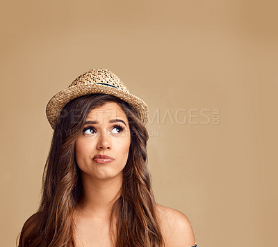 Buy stock photo Studio shot of a beautiful young woman looking thoughtful against a brown background