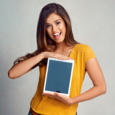 Buy stock photo Studio portrait of an attractive young woman holding a digital tablet with a blank screen against a grey background