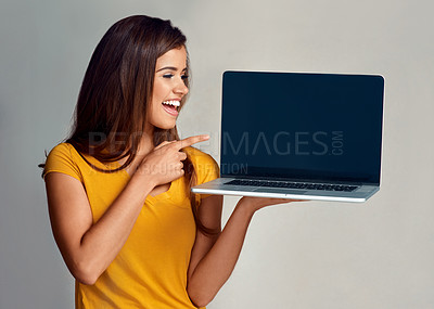 Buy stock photo Studio shot of an attractive young woman pointing to a laptop with a blank screen against a grey background