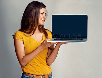 Buy stock photo Studio shot of an attractive young woman holding to a laptop with a blank screen against a grey background