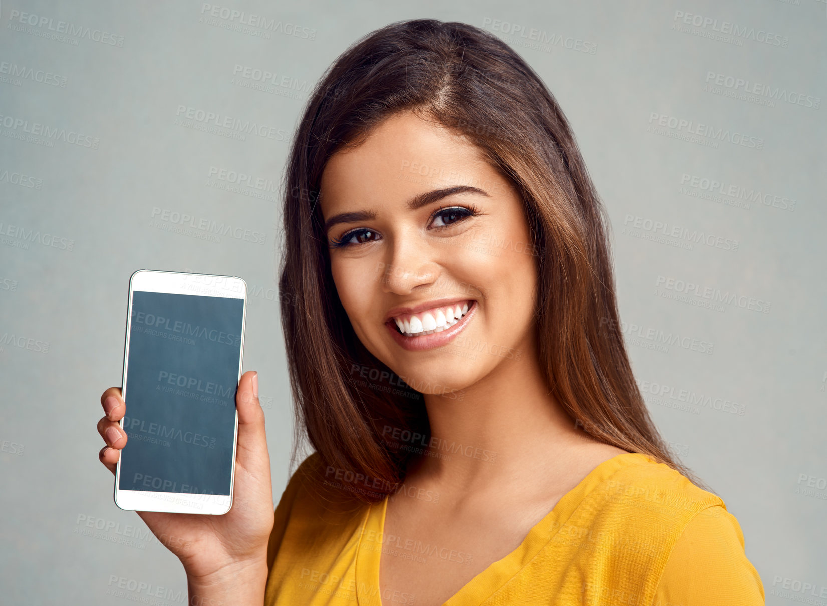 Buy stock photo Happy, woman and display of cellphone in studio with mockup space for advertising, marketing or promotion. Portrait, technology and female person presenting phone screen isolated by gray background.