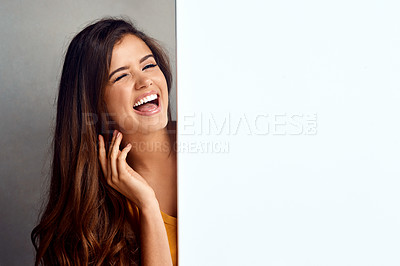 Buy stock photo Studio portrait of an attractive young woman holding a blank placard against a grey background