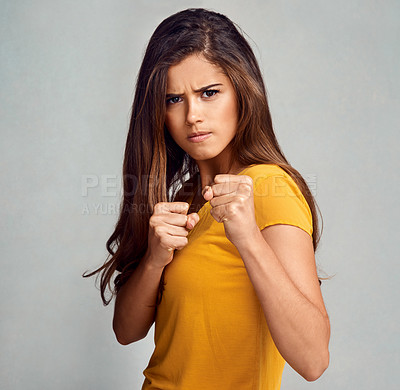 Buy stock photo Studio portrait of an attractive woman putting up her firsts against a grey background