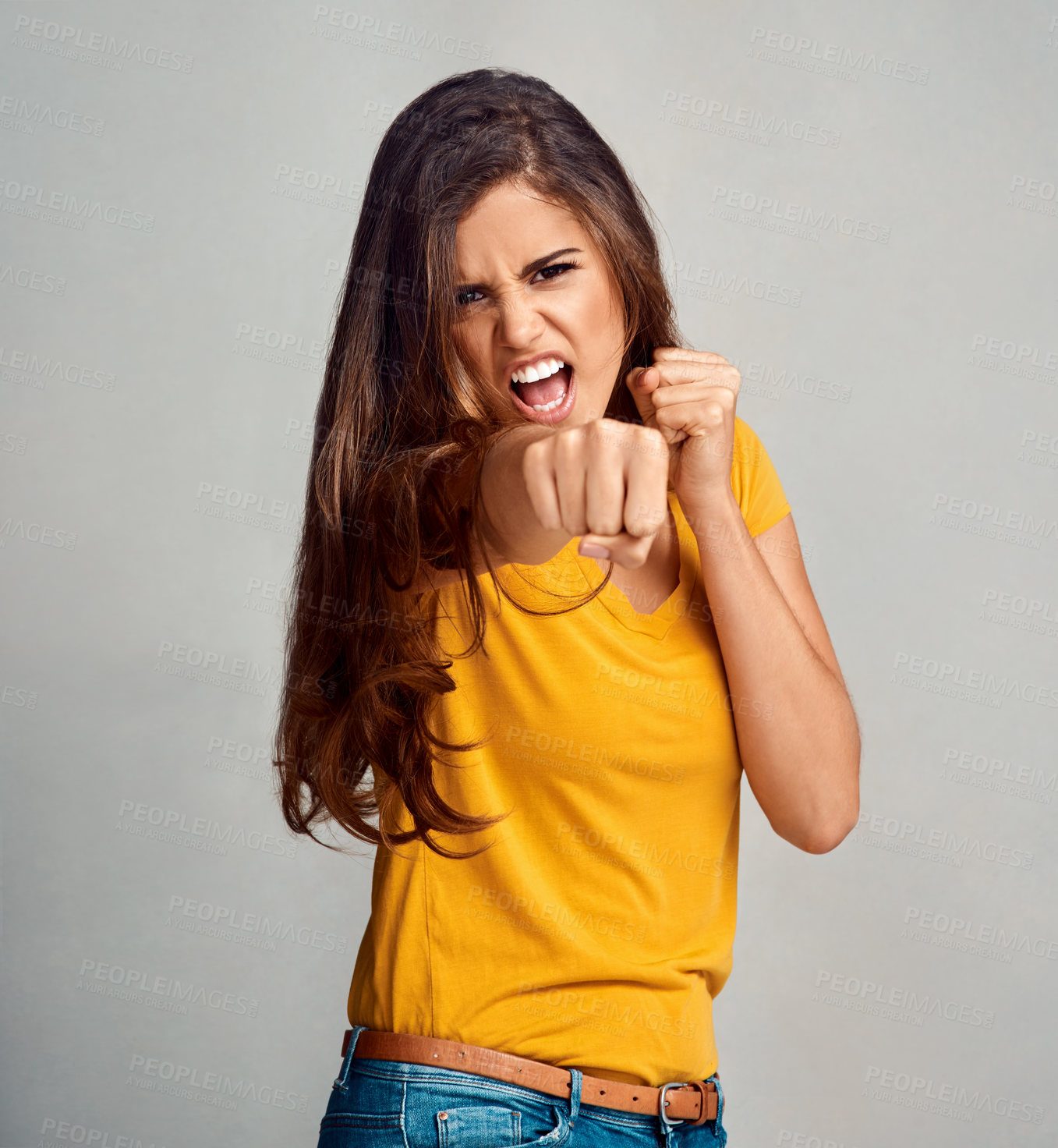 Buy stock photo Portrait, angry woman and fist for fight, conflict and power or protest violence on gray studio background. Face, punch and girl with confidence, strong and scream for boxing attack or self defense