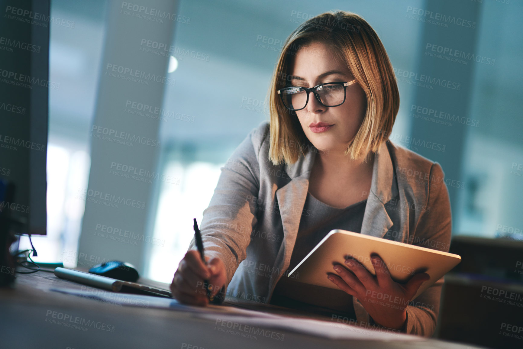 Buy stock photo Shot of a young businesswoman working late on a digital tablet in an office