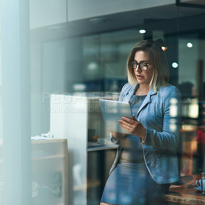 Buy stock photo Shot of a young businesswoman working late on a digital tablet in an office