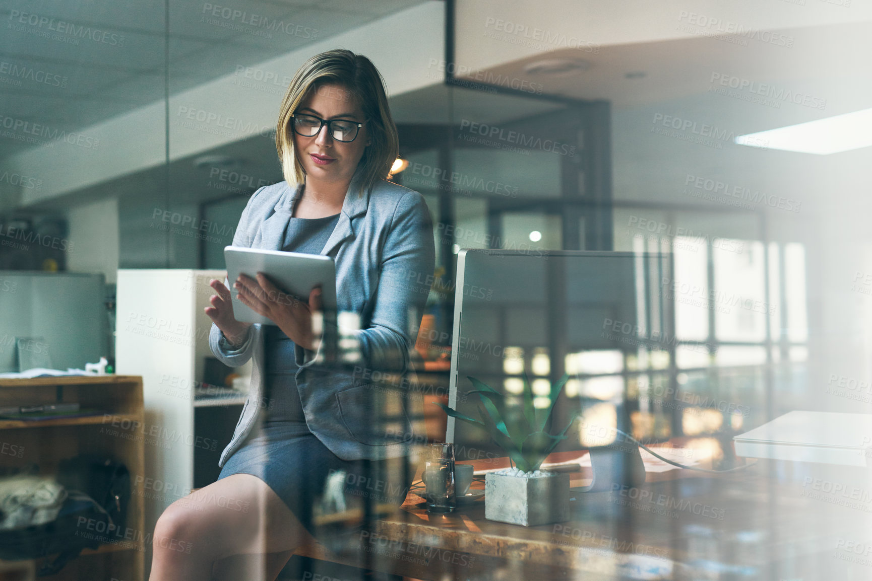 Buy stock photo Shot of a young businesswoman working late on a digital tablet in an office