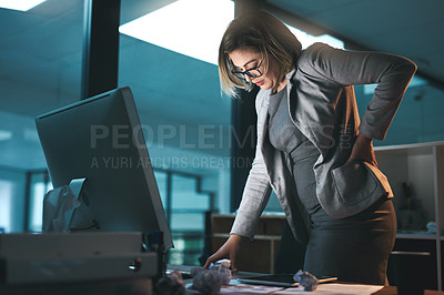 Buy stock photo Shot of a young businesswoman experiencing back pain while working late in an office