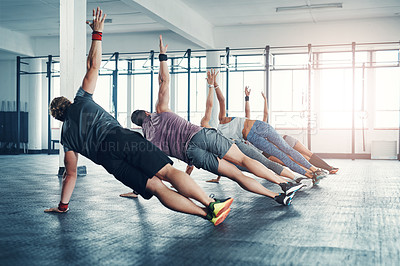 Buy stock photo Fitness, group class and athletes doing a exercise in the gym for health, wellness and flexibility. Sports, training and people doing side plank exercise challenge together in sport studio or center.