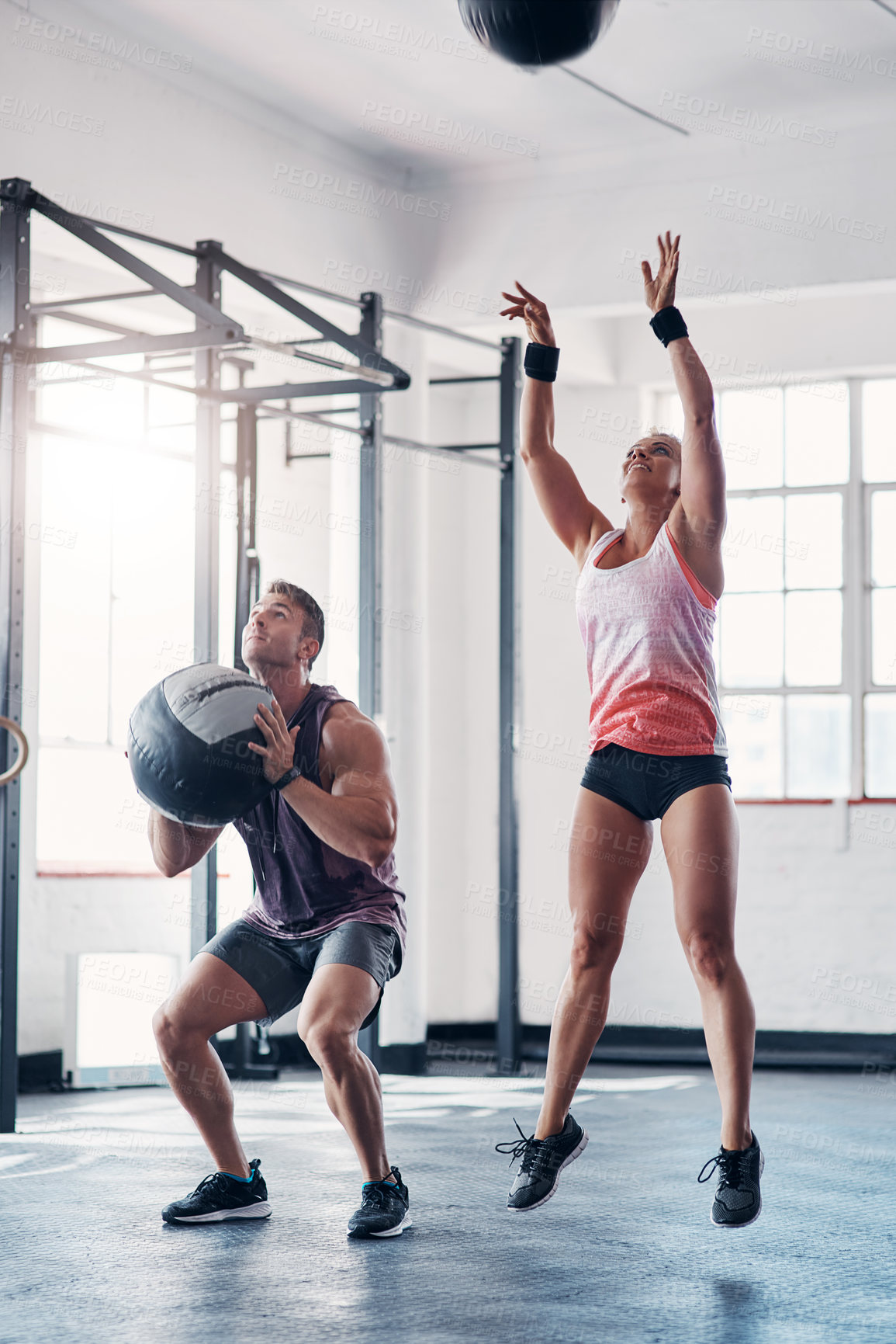 Buy stock photo Shot of two sporty young people working out with medicine balls at the gym