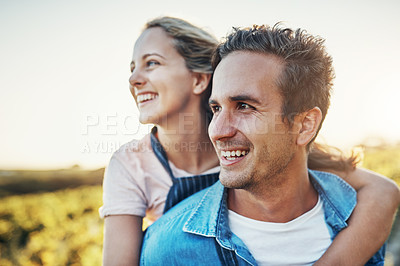 Buy stock photo Cropped shot of a handsome young man piggybacking his girlfriend through the crops on their farm