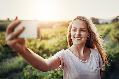 Buy stock photo Cropped shot of a happy young woman taking a photo of herself and her farm in the background