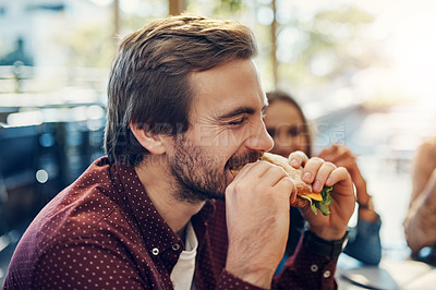 Buy stock photo Cropped shot of a handsome young businessman enjoying his sandwich while having a breakfast meeting outside