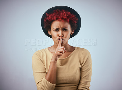 Buy stock photo Shot of a beautiful young woman posing with her finger on her lips against a gray background
