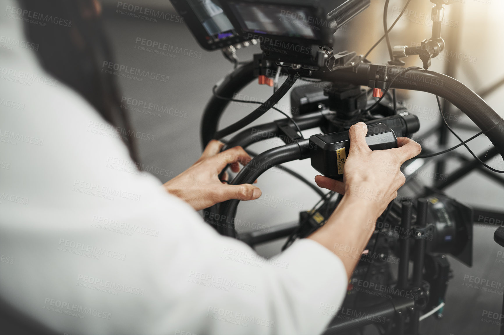 Buy stock photo Behind the scenes over the shoulder shot of an unrecognizable person operating a state of the art video camera inside of a studio