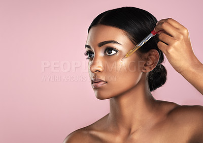 Buy stock photo Face, skincare serum and serious woman in studio isolated on a pink background mockup. Dermatology, cosmetics and Indian model with hyaluronic acid, essential oil or vitamin c dropper for skin health