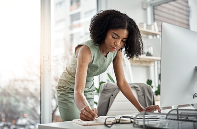 Buy stock photo Shot of a young businesswoman writing in a notebook at her desk in a modern office