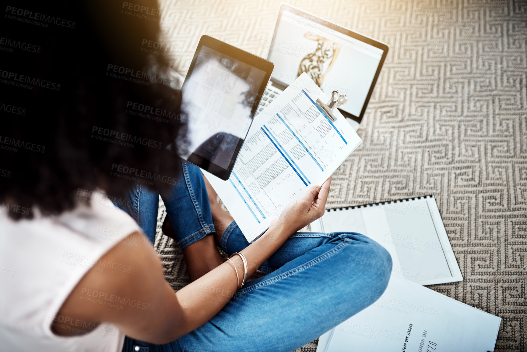 Buy stock photo High angle shot of an unrecognizable young businesswoman looking over some paperwork while working in her home office