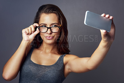 Buy stock photo Studio shot of an attractive young woman taking a selfie against a grey background