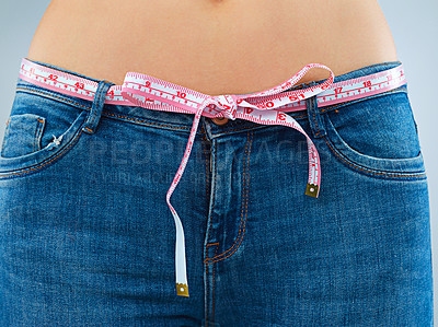 Buy stock photo Stomach, weight loss and woman with tape, progress and health goals on studio background. Tummy, person and model in jeans, diet and wellness with belly, fitness and closeup for body measurements