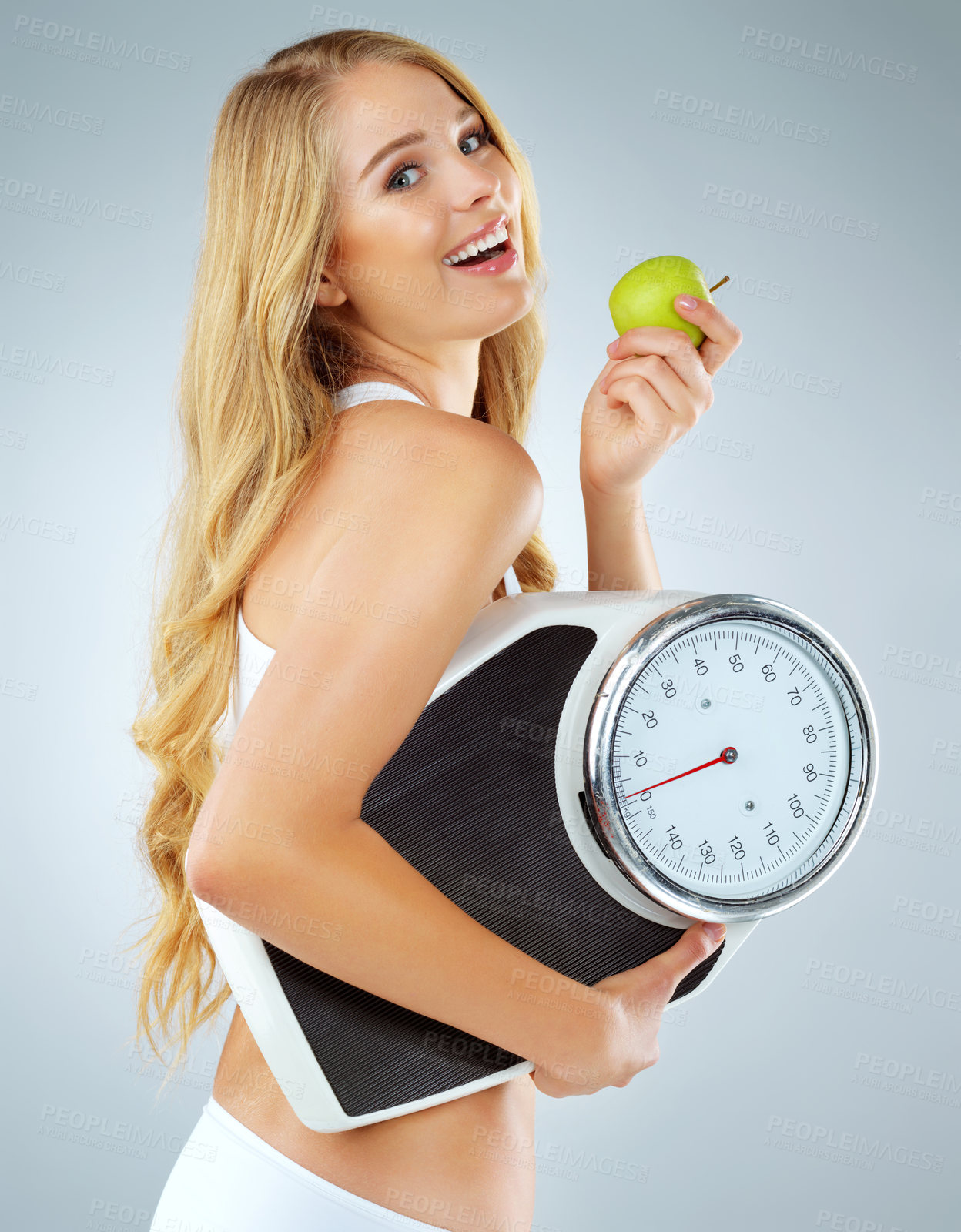 Buy stock photo Portrait, scale and happy woman with apple in studio for body goal, organic diet or nutrition on gray background. Fitness, smile and model with weight loss for wellness, results or workout progress