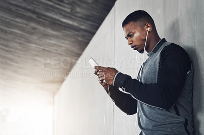 Buy stock photo Cropped shot of a handsome young man sending a text while exercising outside