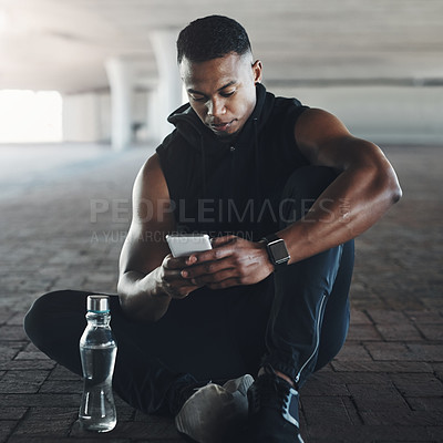 Buy stock photo Black man, phone and break from exercise in city with texting, reading or relax on ground with fitness. Male person, smartphone and runner with contact, app or social media on concrete in New York