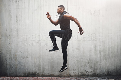 Buy stock photo Full length shot of a handsome young man skipping on the spot while exercising outside