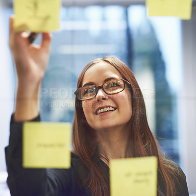 Buy stock photo Cropped shot of a young businesswoman brainstorming on a glass wall in an office