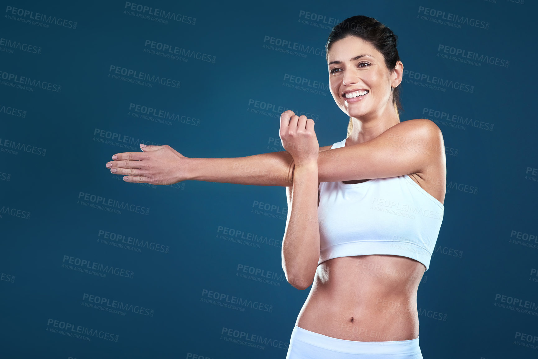 Buy stock photo Woman, fitness and stretching arm in studio for wellness, thinking and happy for training on blue background. Young sports person, athlete or model with idea for body and joint in pilates or exercise