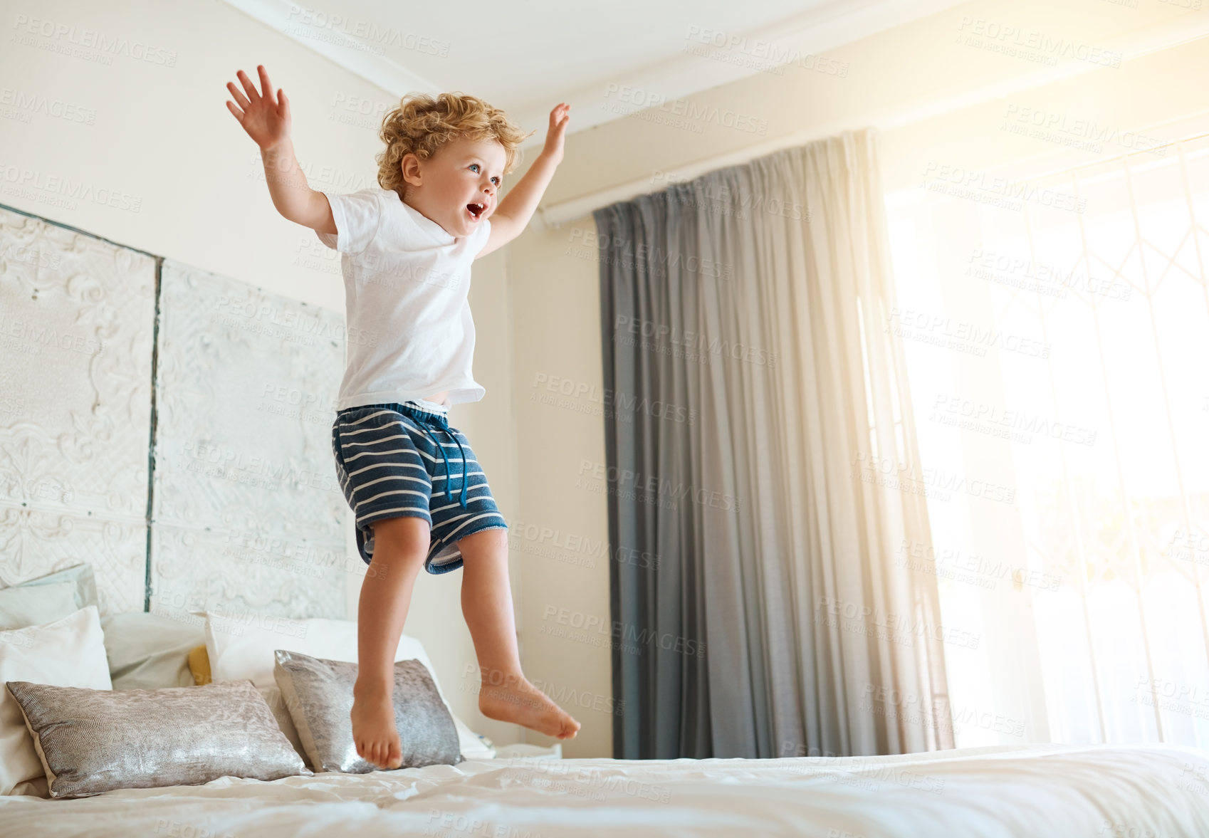 Buy stock photo Shot of an adorable little boy jumping on the bed at home