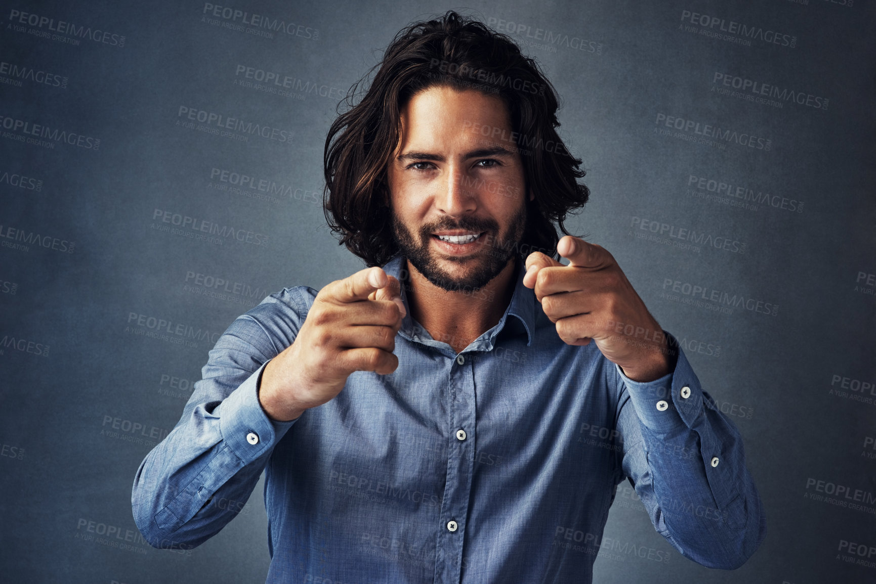 Buy stock photo Studio portrait of a handsome young man pointing at the camera while posing against a grey background