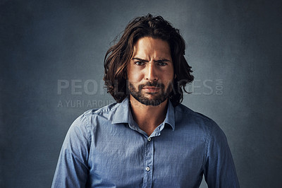 Buy stock photo Serious man, portrait and fashion with hairstyle, beard or frown for attitude on a gray studio background. Handsome male person or young model with facial expression, aggression or casual tshirt 