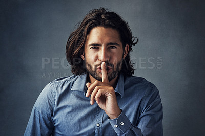 Buy stock photo Studio portrait of a handsome young man posing with his finger on his lips against a grey background