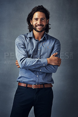 Buy stock photo Studio portrait of a handsome young man standing with his arms folded against a grey background