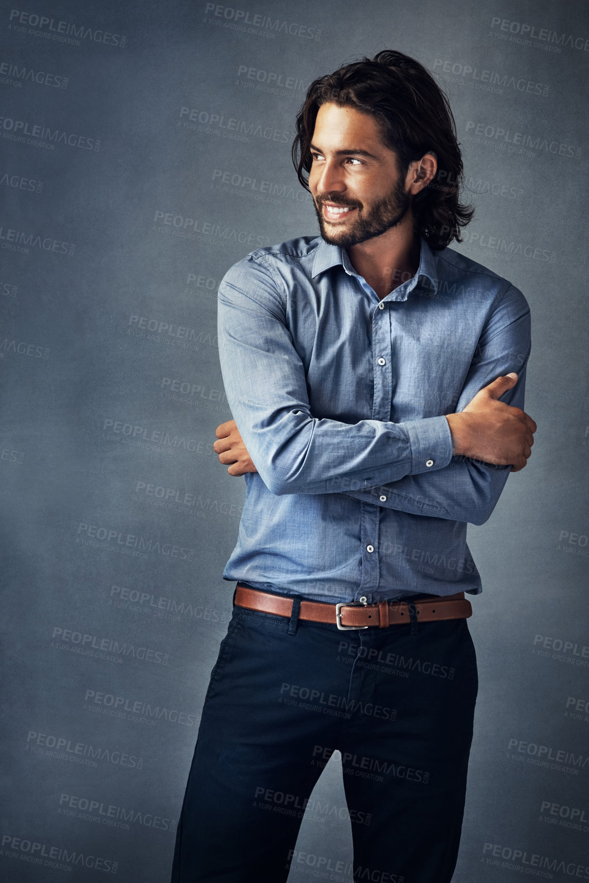 Buy stock photo Studio shot of a handsome young man standing with his arms folded against a grey background