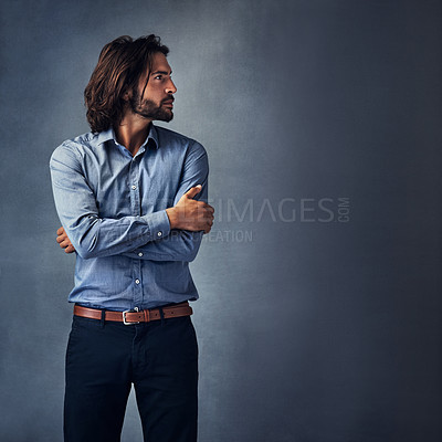 Buy stock photo Studio shot of a handsome young man standing with his arms folded against a grey background