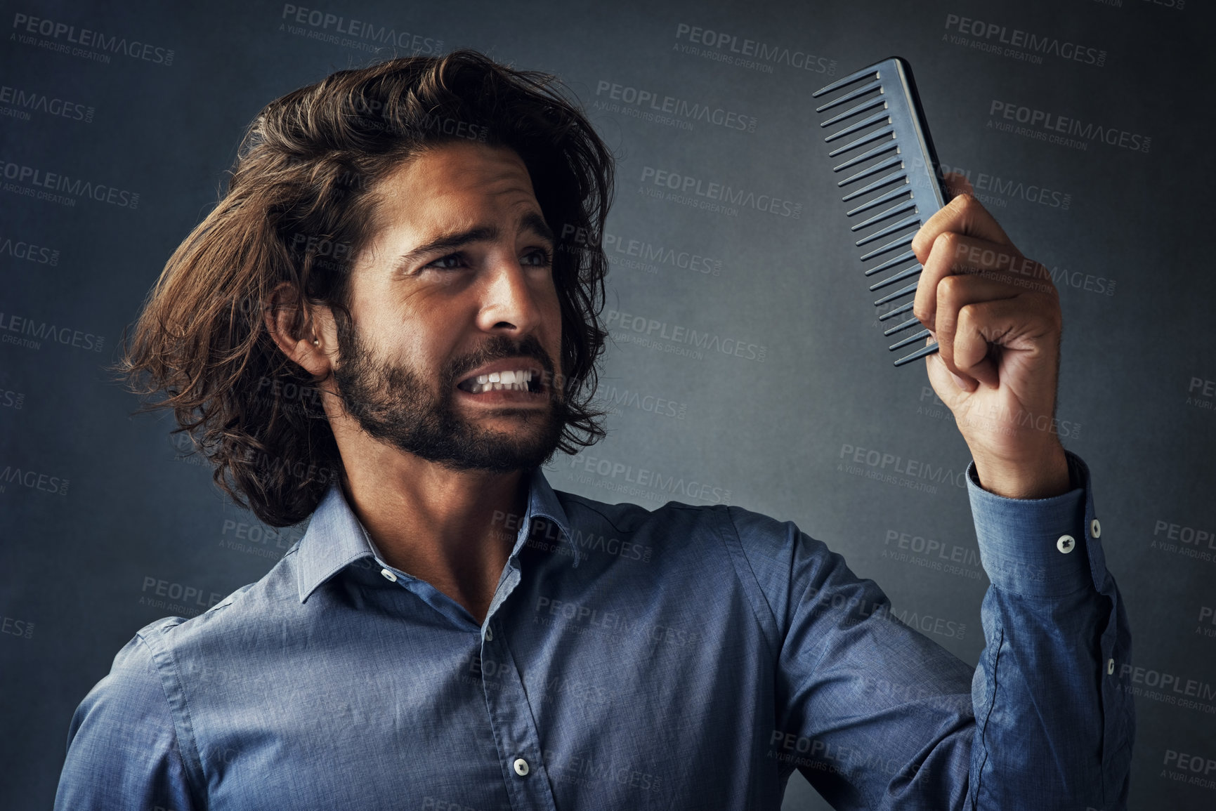 Buy stock photo Frustrated man, haircare and doubt with comb for grooming, morning or routine on a gray studio background. Handsome male person or model with brush for beard maintenance or facial hair treatment