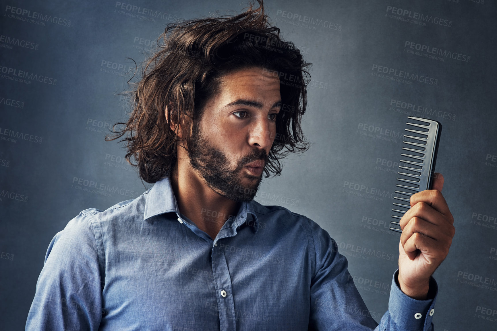 Buy stock photo Frustrated man, fashion and haircare with comb for grooming, morning or routine on a gray studio background. Handsome male person or model with brush for beard maintenance or facial hair treatment