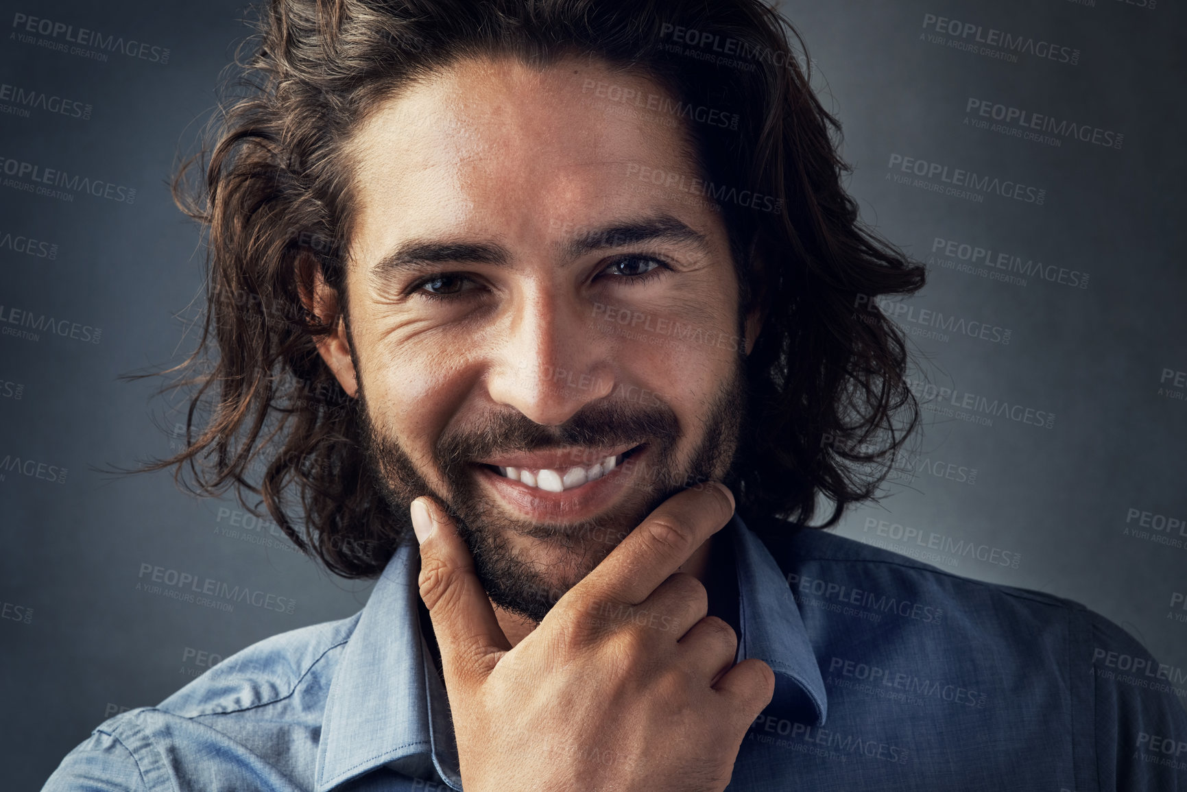 Buy stock photo Studio portrait of a handsome young man posing with his hands on his chin against a grey background
