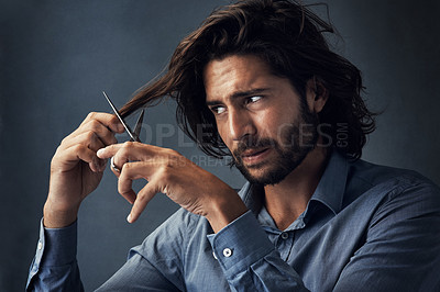 Buy stock photo Studio shot of a handsome young man cutting his hair against a grey background