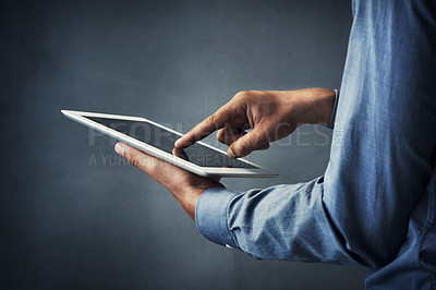 Buy stock photo Cropped shot of an unrecognizable man using a digital tablet against a grey background
